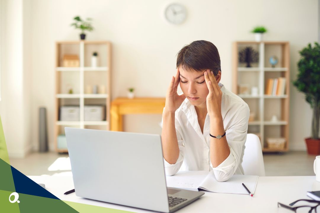 Frustrated woman sitting at a desk with a laptop, holding her head in her hands while looking at the screen, indicating stress or fatigue. Accord Consulting logo in bottom left corner.