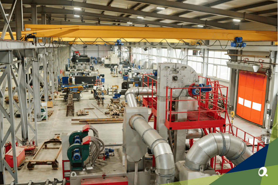 Wide shot of a modern equipment manufacturing facility with machinery, overhead cranes and workers on the shop floor.