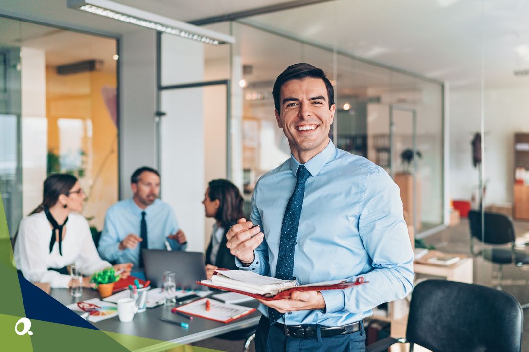 Finance leader smiling at the camera, standing in front of his finance team working with a new Sage Intacct system