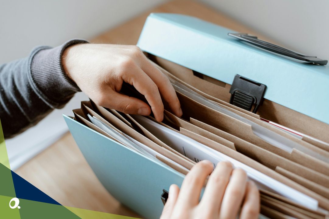 Close-up of a person sorting through paper files in a document folder, representing manual financial processes.