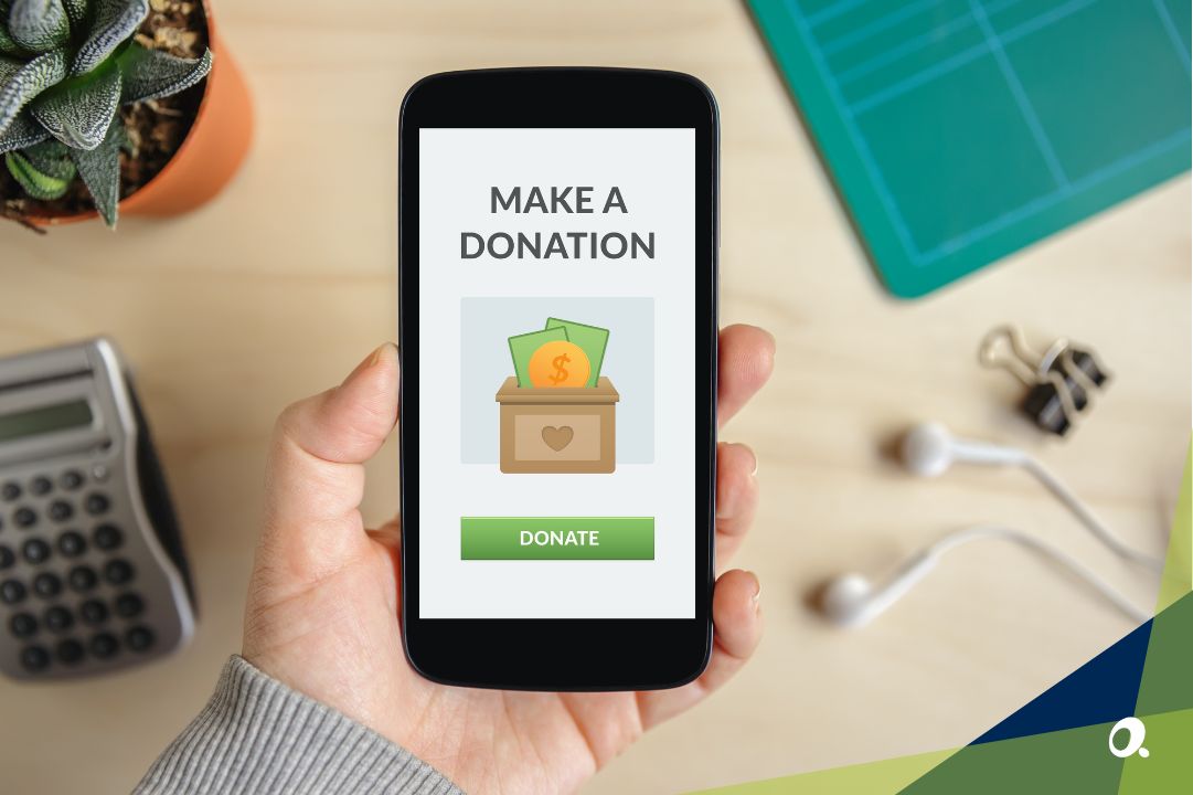 Hand holding smartphone showing a make a donation screen with a green donate button