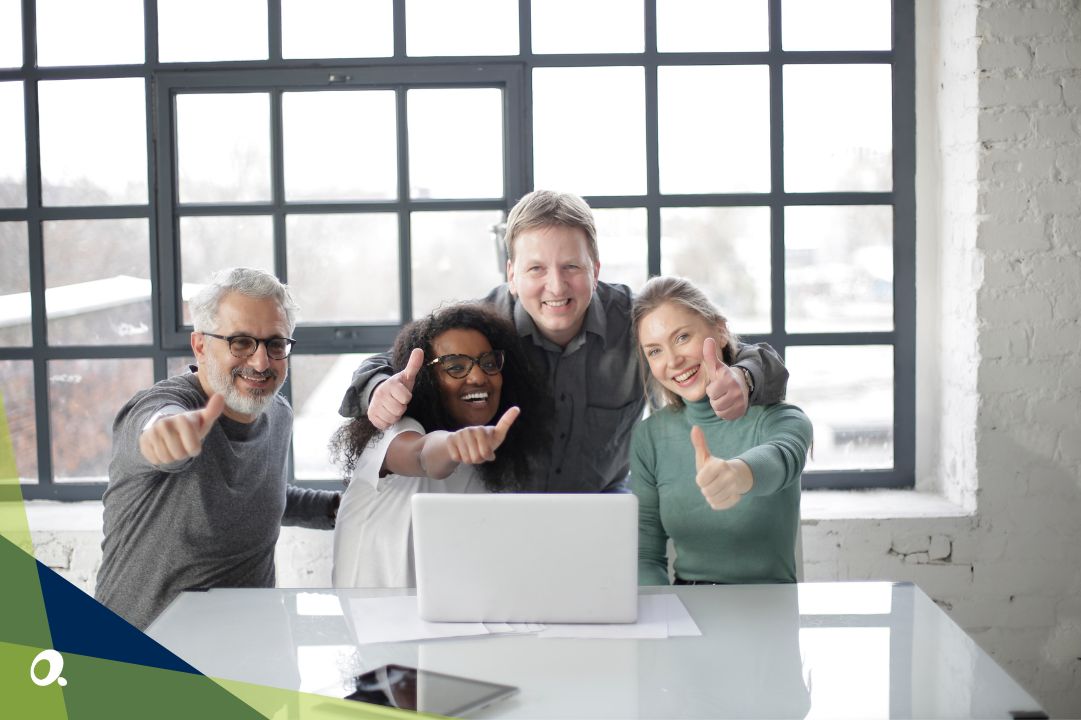 Finance team gathered around a laptop, showing thumbs up
