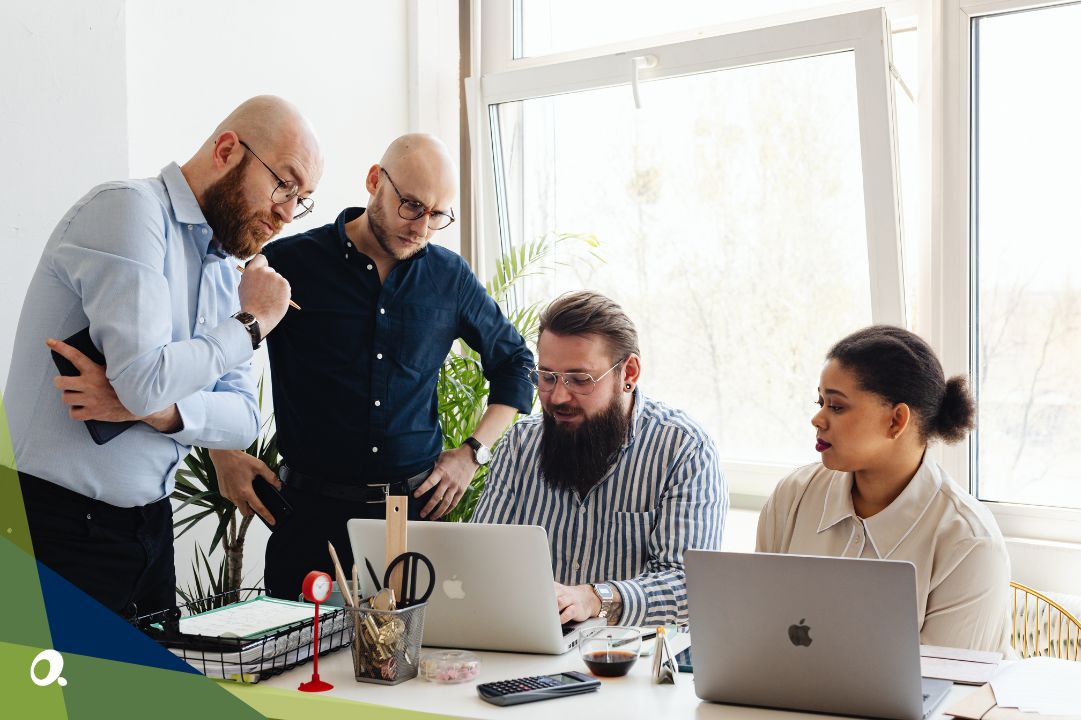 Team of finance professionals reviewing data together at a desk with laptops, illustrating collaboration across multi-entity operations