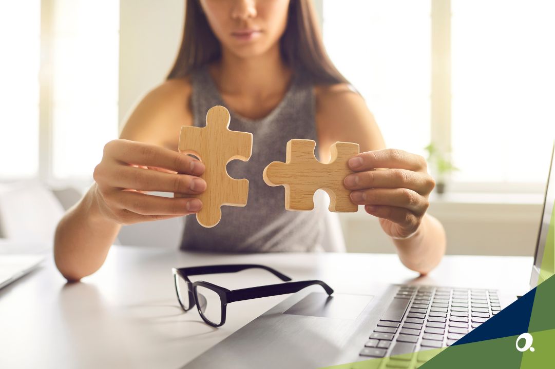 Person holding two wooden puzzle pieces, symbolising connecting systems for finance integration.