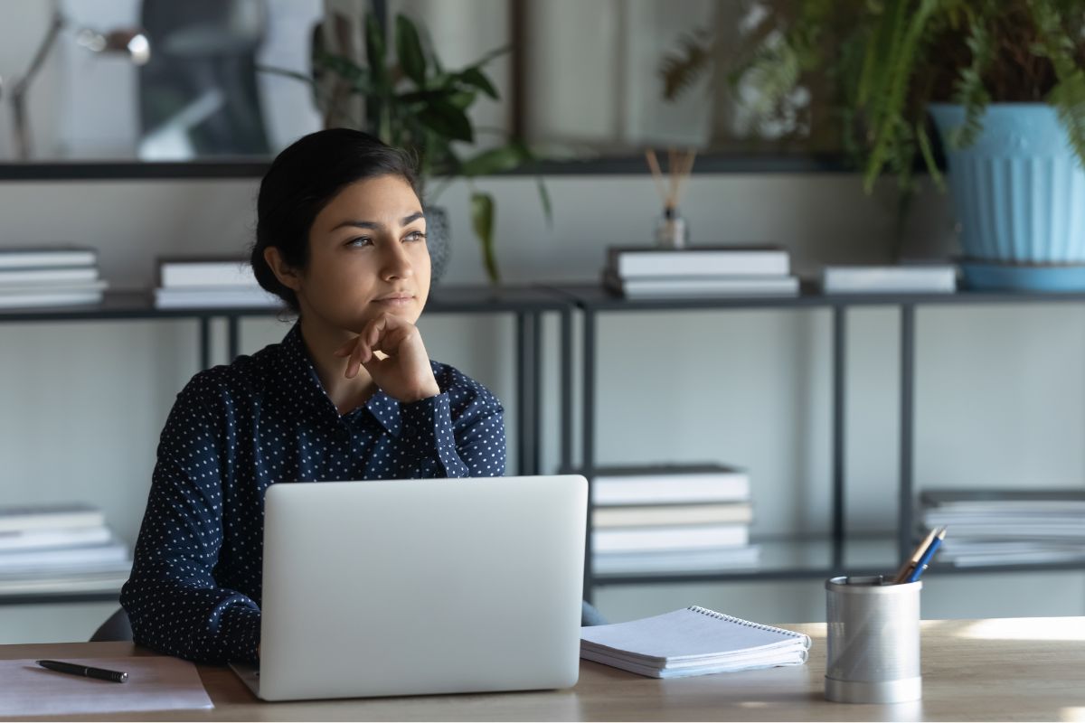 Professional woman sitting in front of a laptop, thinking